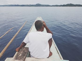 Rear view of man sitting on boat in sea