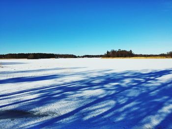 Scenic view of snow covered landscape against clear blue sky