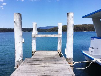 Wooden posts in sea against clear blue sky