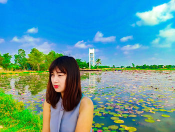 Thoughtful young woman sitting against lake