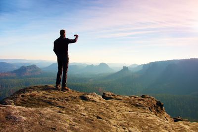 Full length of man standing on rock against sky