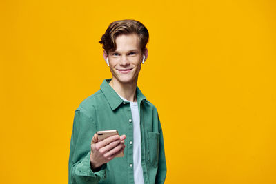 Portrait of young woman standing against yellow background