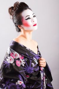 Woman wearing make-up and traditional clothing while standing against white background