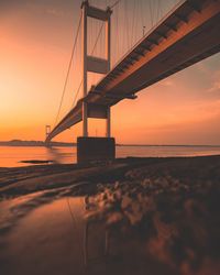 Bridge over sea against sky during sunset