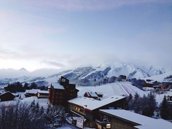 Buildings and snowcapped mountains against sky