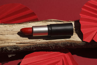 Red lipstick on wooden podium with paper craft on red background. 