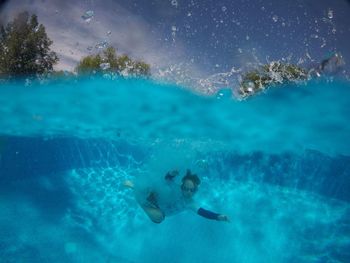 Boy swimming in pool against sky