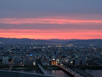 Illuminated cityscape against sky during sunset