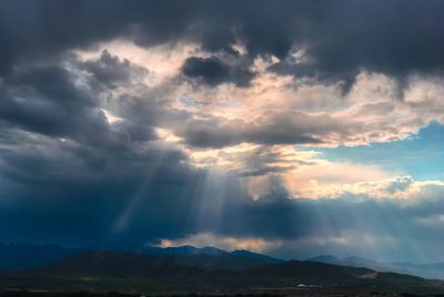 Scenic view of rainbow over landscape against storm clouds