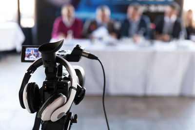 Close-up of television camera in front of people in seminar