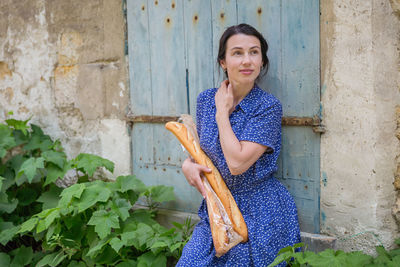 Young woman standing with french baguettes in the countryside