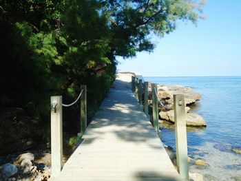 Walkway by sea against sky