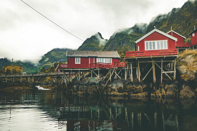 Houses by lake and buildings against sky in norway