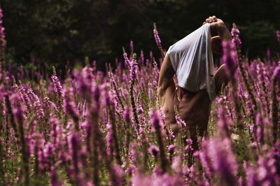 Man removing t-shirt while standing amidst plants