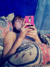 Low section of woman photographing with mobile phone on bed