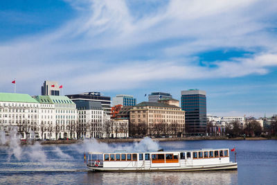 Boats in river by buildings in city against sky