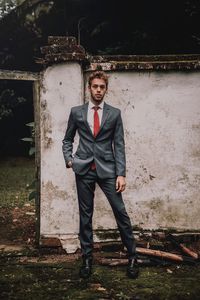 Portrait of young man standing against wall