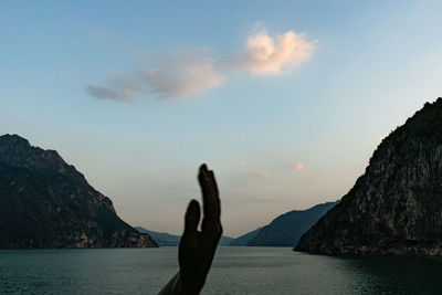 Man on rock by sea against sky