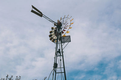 Low angle view of american-style windmill against cloudy sky