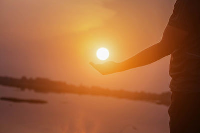 Silhouette person standing on rock against sky during sunset