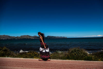 Woman by sea against clear sky