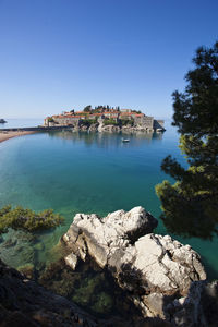 Buildings by sea against clear blue sky