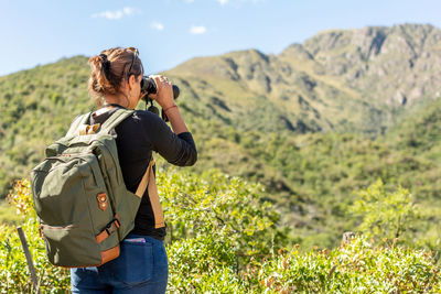 Rear view of man photographing on mountain