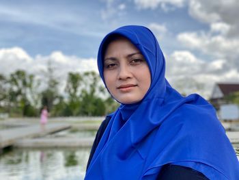 Portrait of hijab woman standing against blue sky