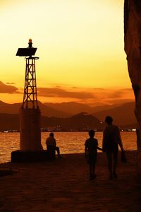 Silhouette people standing at beach during sunset