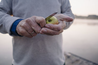 Man cutting apple while standing outdoors