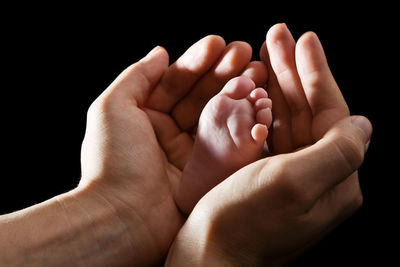 Close-up of baby hand against black background