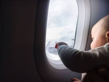 Close-up of child looking towards airplane window
