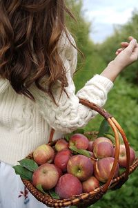 Midsection of woman holding strawberries in basket