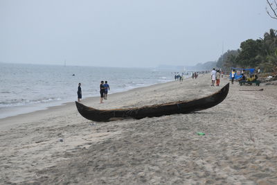 People on beach against clear sky