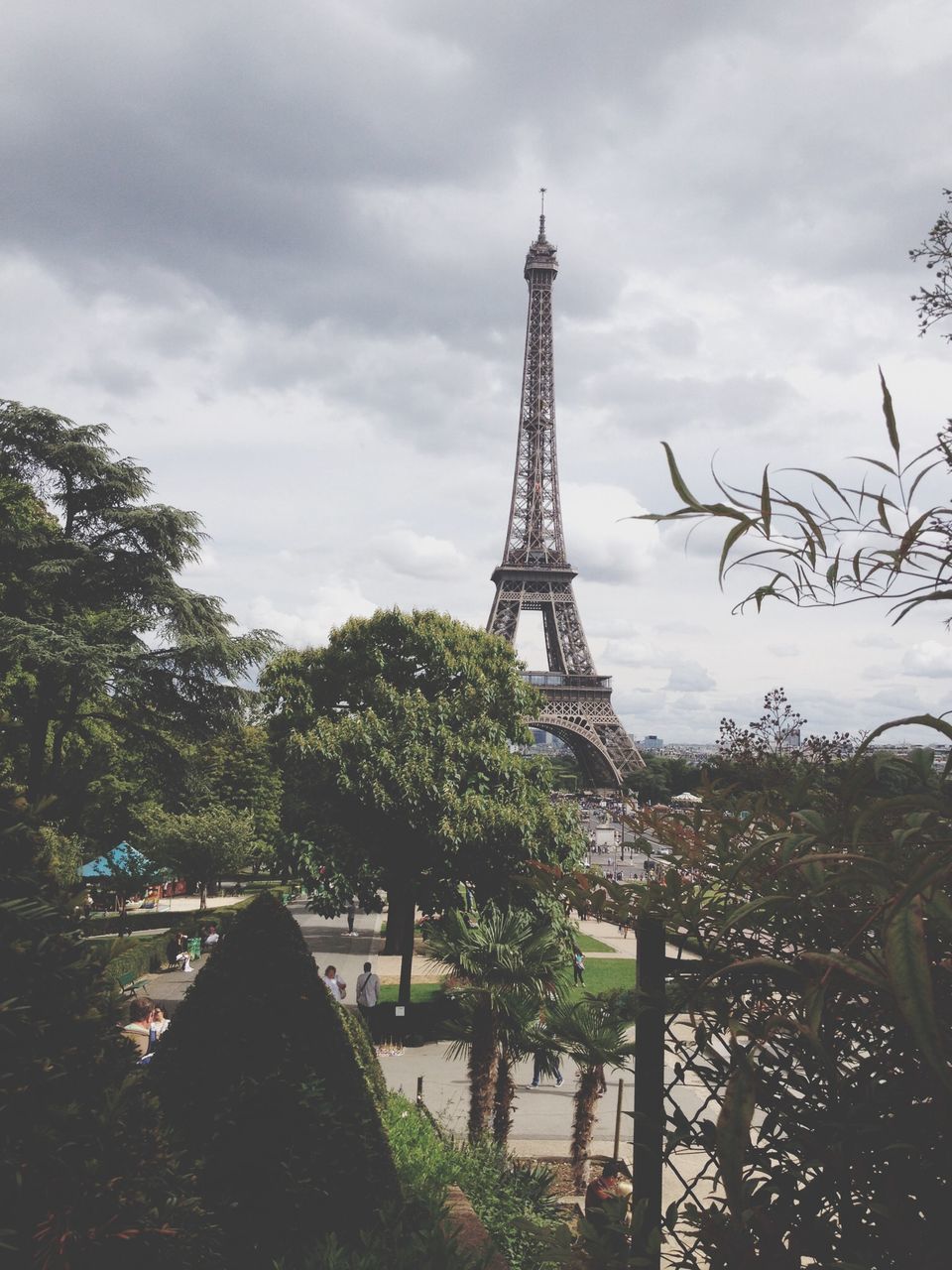 eiffel tower, built structure, architecture, sky, tree, tower, metal, culture, famous place, tall - high, travel destinations, international landmark, cloud - sky, building exterior, history, capital cities, low angle view, tourism, cloudy, day