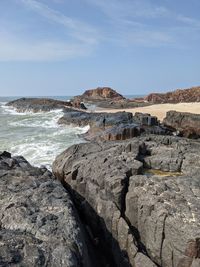 Rock formation on beach against sky