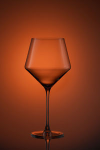 Close-up of wineglass on table against orange background