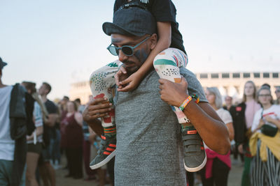 Rear view of people holding sunglasses against sky