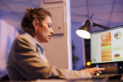 Side view of woman using mobile phone in office