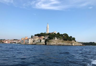 Buildings by sea against sky