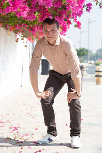 Full length of young man against pink flowers