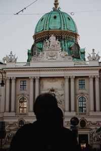 Rear view of man outside building against sky