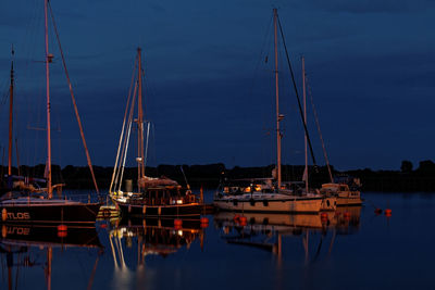 Sailboats moored in harbor at night