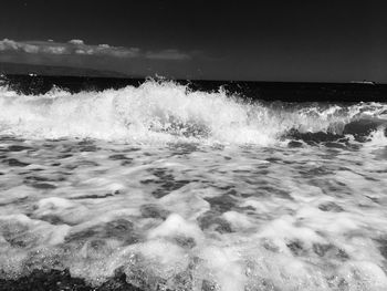 Waves splashing on shore against clear sky