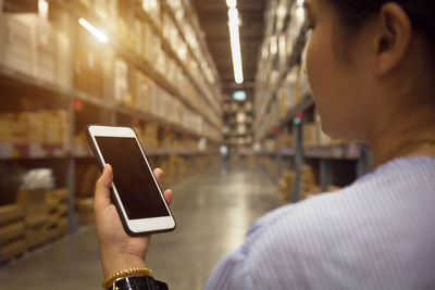 Close-up of woman using blank phone in warehouse