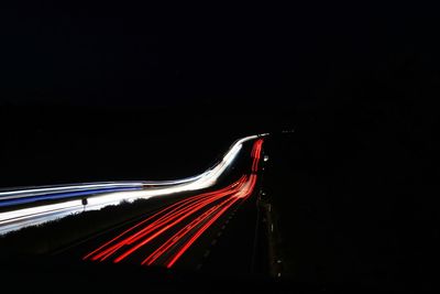 Light trails on road against sky at night