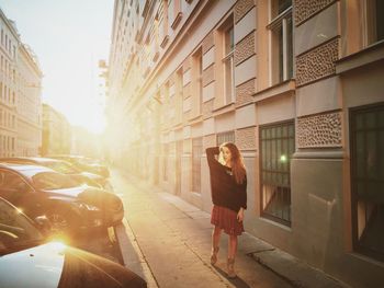 Young woman walking on sidewalk by building in city