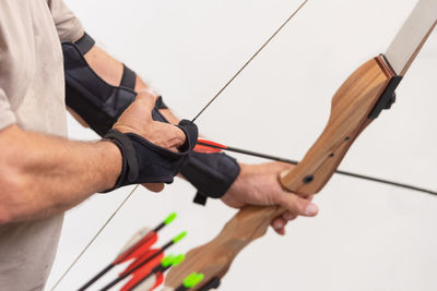 Midsection of man aiming with arrow against clear sky