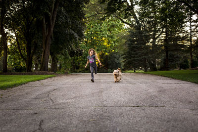 Girl running with dog on leash