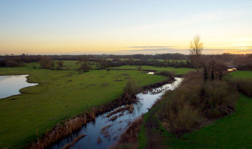 Scenic view of farm against sky during sunset